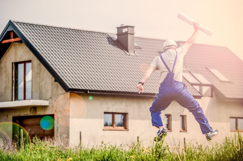 Man jumping with building plans and house in background